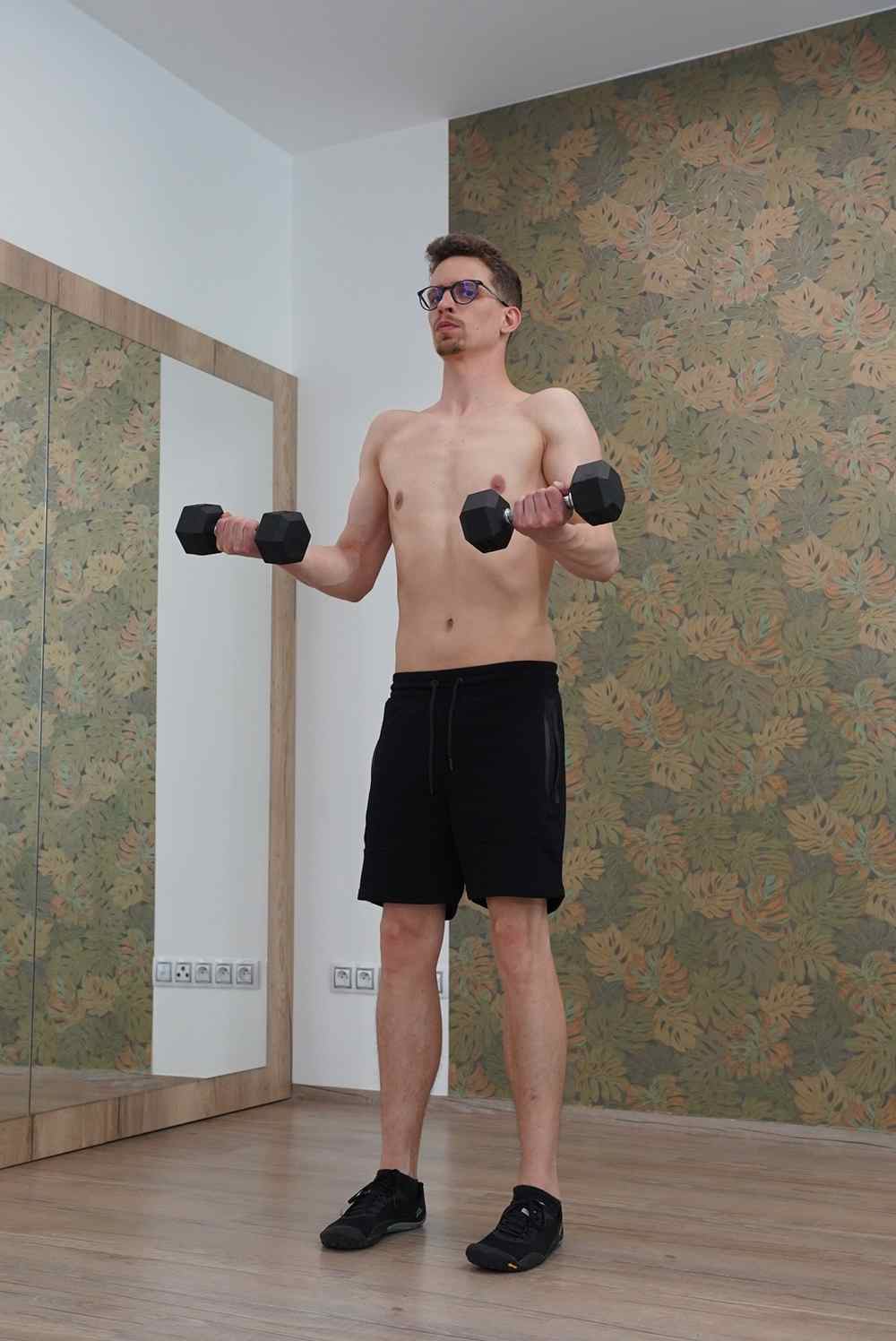 Muž cvičí v poloze na boku s jednoručkami