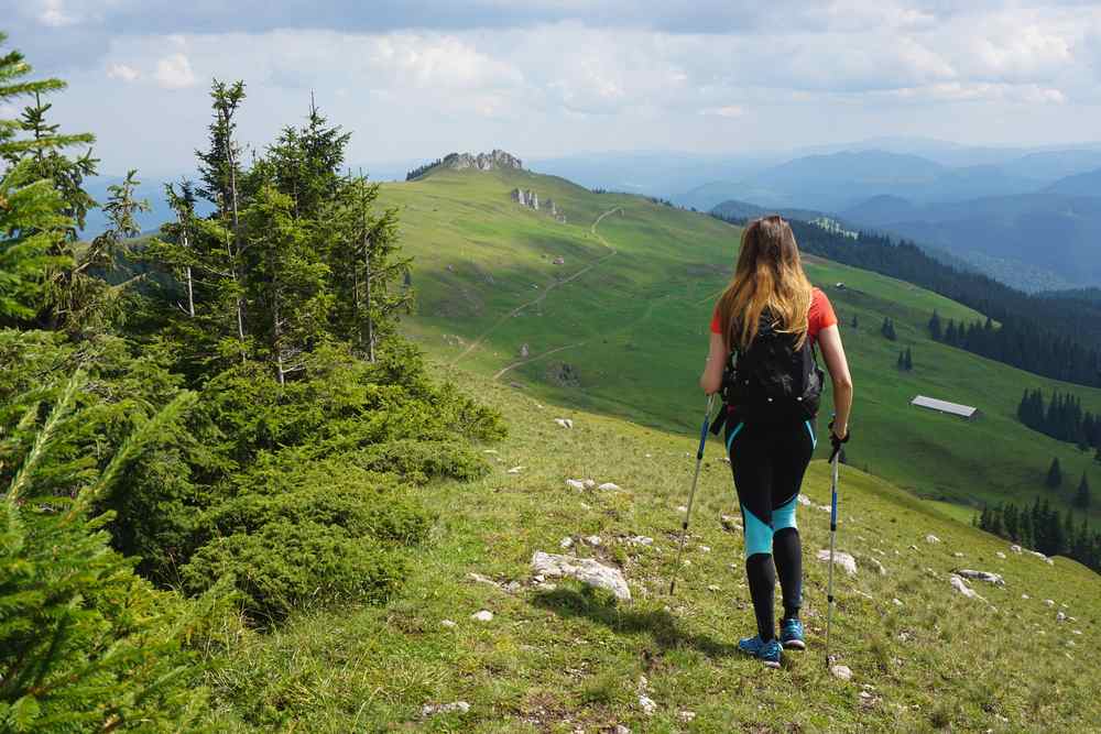 Turistka na horském hřebeni pod modrou oblohou