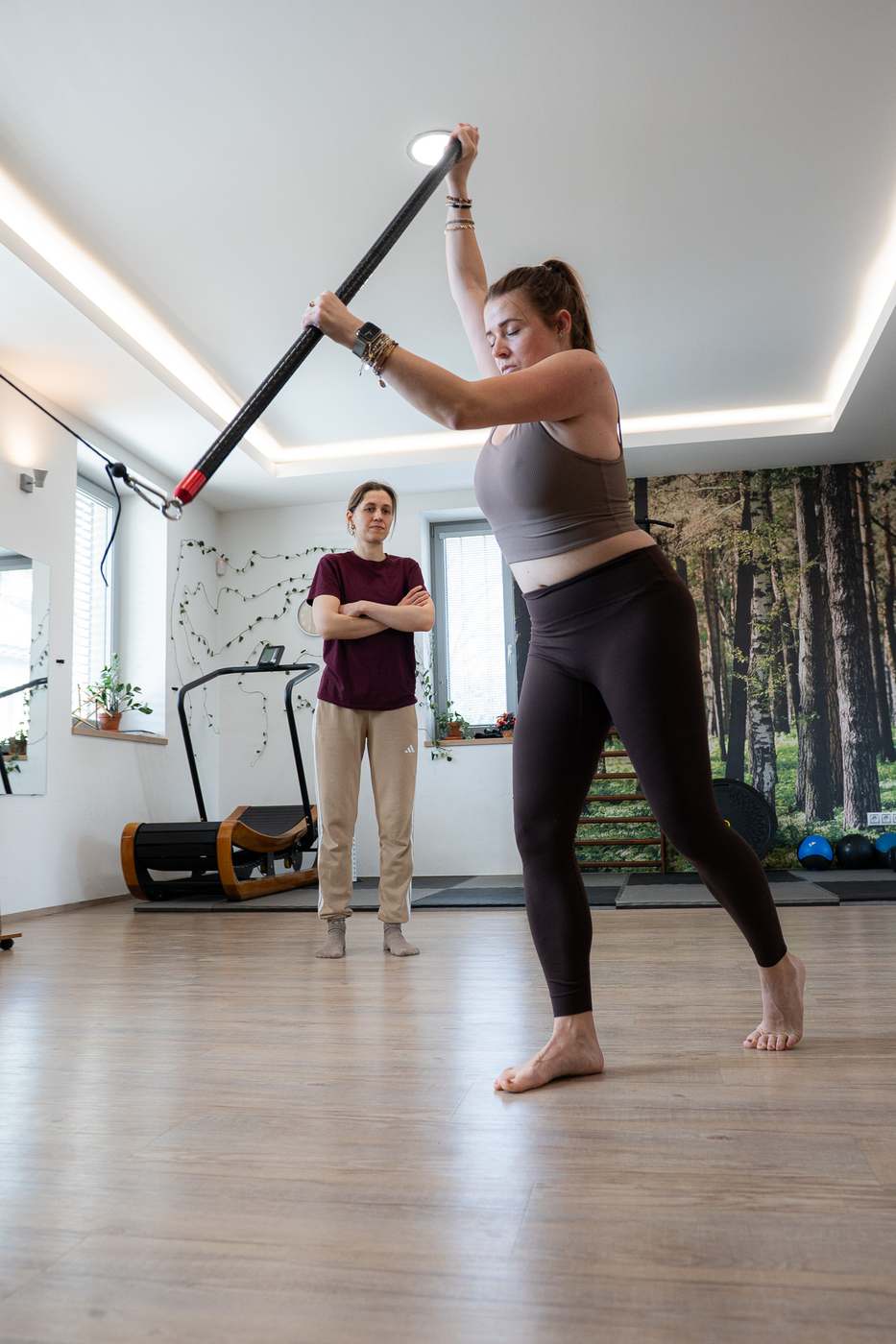 Klientka při cviku s tyčí nad hlavou