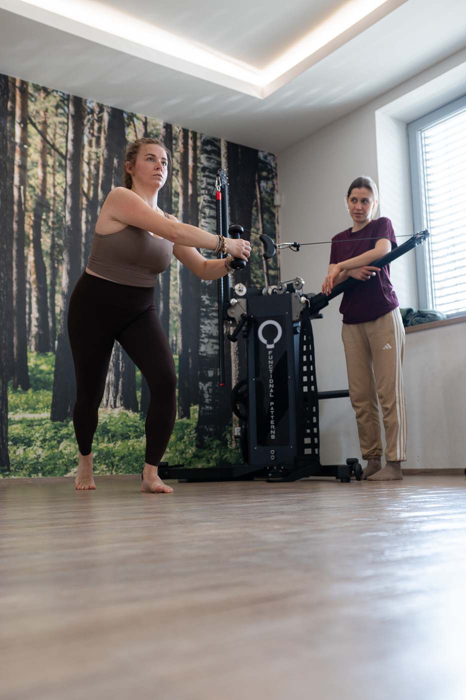 Klientka při cviku s kladkou u lesní tapety