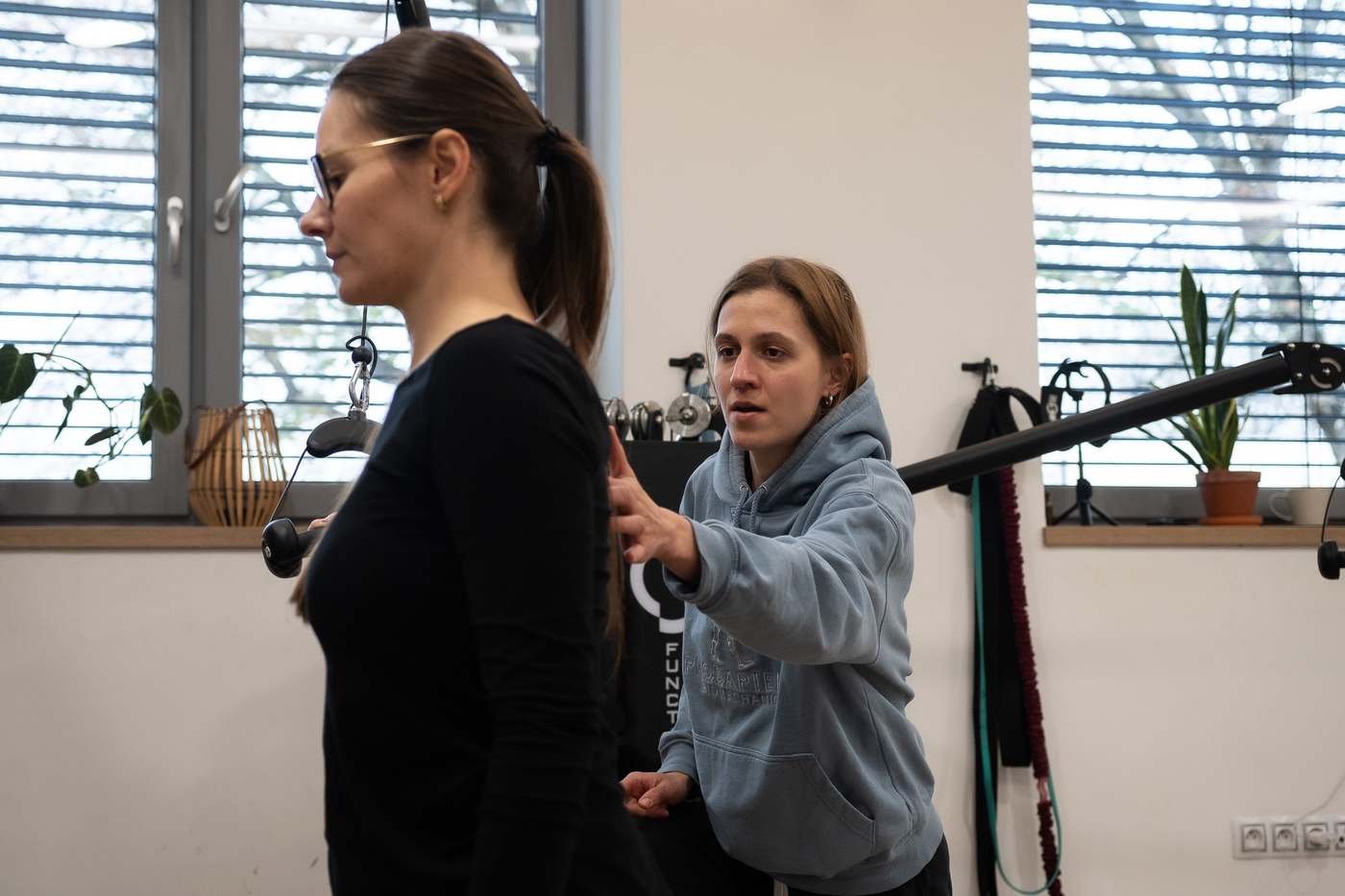 Trenérka vede klientku při cviku s tyčí