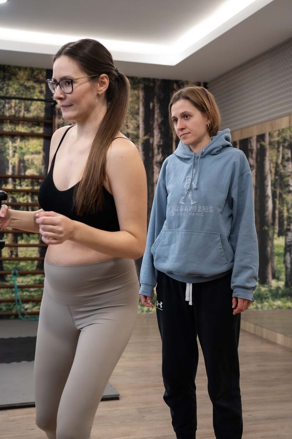 Klientka ve stoji, trenérka sleduje držení těla