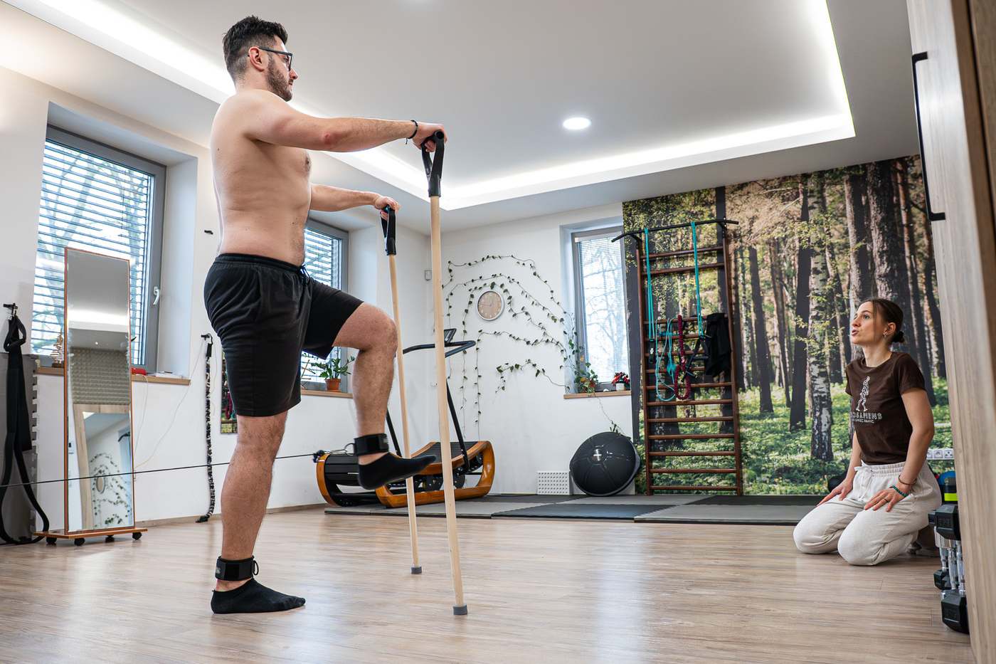 Klient při cviku s holí, trenérka sleduje